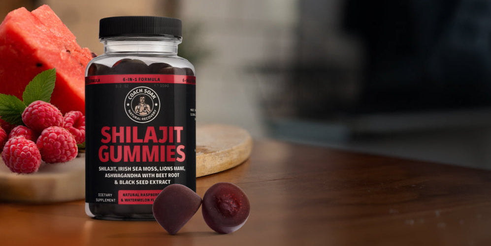 Bottle of Shilajit Gummies with a blurred background of fruits on a wooden surface